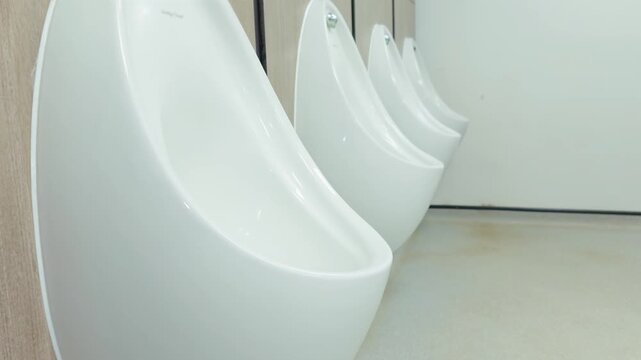 White ceramic urinals standing in public restroom interior promoting hygiene awareness. Sanitary facility environment supporting bacteria control and cleanliness maintenance improving health safety