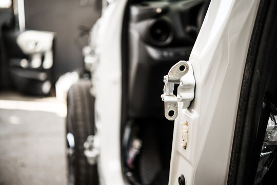 Closeup of car door hinge inside automotive repair body shop