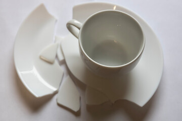 Broken cup and saucer pieces on a flat surface showing damage and loss of a ceramic item without any visible background