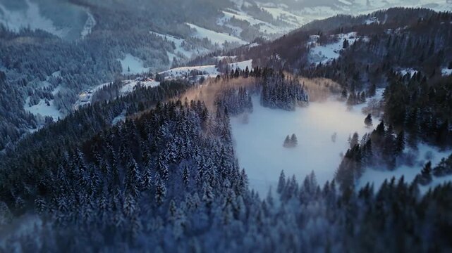Aerial tilt-shift view of a snowy forest and mountain village at dusk.