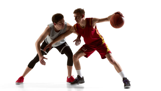 Two young basketball players competing for ball in studio isolated on white background. Concept of sports academy advertising, basketball camp promotion, and athletic training program marketing.