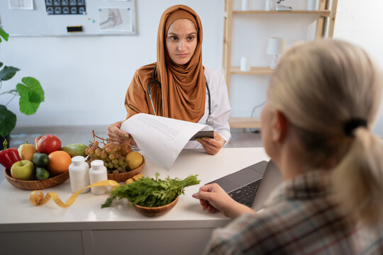 Arabian woman dietitian or nutritionist consultation for overweight female patient about healthy food and presenting diet plan