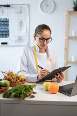 Female nutrition advisor making meal plan during work at weight loss clinic. dietitian in white coat writing prescription for patient © Andrii Lysenko