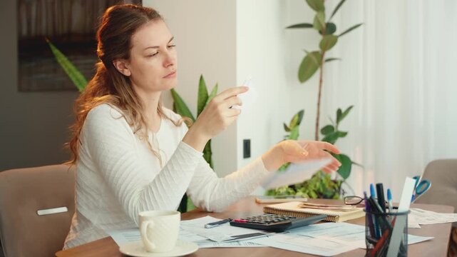 worried face upset female views mail letters expenses planning budget. Stressed sad tired depressed young woman sitting at desk checking utility bills taxes bank account balance calculating expense