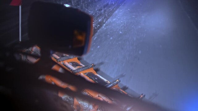 Close and elevated views of a snowplow blade pushing heavy snow off a highway at night. Blowing snow, icy asphalt and warning lights capture intense winter conditions and active road maintenance work.