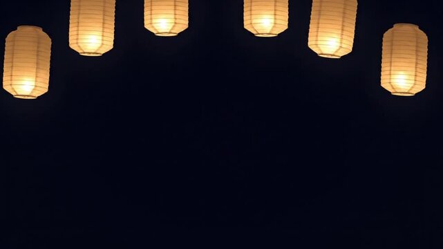 A row of traditional Japanese lanterns illuminated against a dark night sky, creating a serene and festive atmosphere