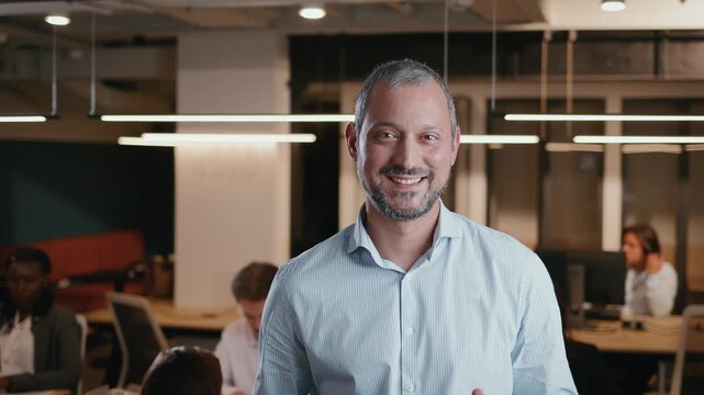 Mature businessman smiling confidently in a modern open-plan office