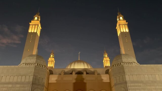 Sultan Qaboos Mosque in Nizwa featuring elegant Islamic architecture and illuminated minarets at night.