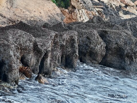 Waves over weathered rocks and pools, Sea surge causes erosion on coastal rock formations and pools