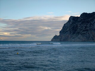 Naklejka premium Churning ocean meets perilous rocky coastline, Unsettled weather with crashing waves against rugged cliffs