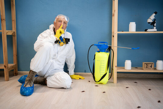 Pest exterminator sitting on floor showing shh gesture. disinfection service at home. pest control for cockroaches. sprayer chemicals