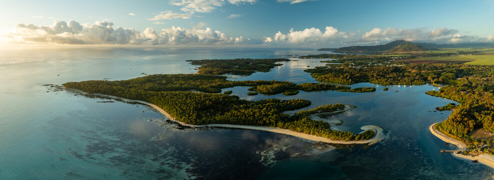 Aerial view of lush green islands embraced by the azure sea, where the golden light kisses the tranquil waters, Shangri La, Trou d'Eau Douce, Mauritius.