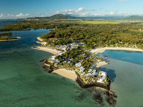 Aerial view of a serene coastal haven where turquoise waters gently kiss the sandy shores, fringed by lush greenery, Shangri La, Trou d'Eau Douce, Mauritius.