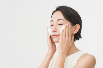 スキンケアプロセス。洗顔フォームの泡で洗顔をしている女性。