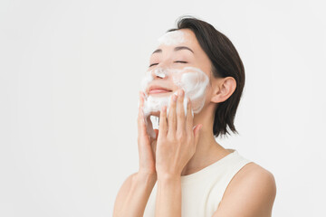 スキンケアプロセス。洗顔フォームの泡で洗顔をしている女性。