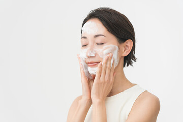 スキンケアプロセス。洗顔フォームの泡で洗顔をしている女性。
