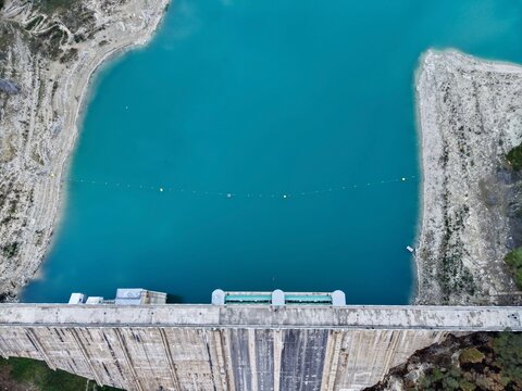 Dam reservoir reflecting tranquil waters, Calm surface of water behind dam with vibrant turquoise pools