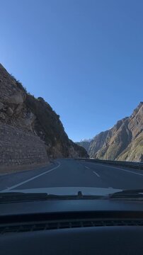Point of View Shot from a Car Driving through Majestic High Mountain Pass with Clear Blue Skyroad to the mountains