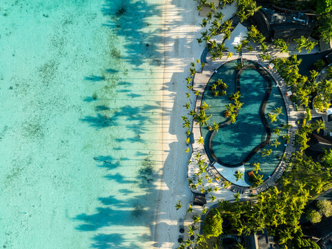 Aerial view of the turquoise waters meeting the white sands next to an oval pool fringed with palms, Royal Trou Aux Biches Rd, Triolet, Pamplemousses, Mauritius.