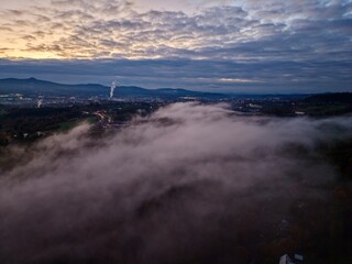silent town shrouded in night fog, serene village beneath luminous lights and drifting clouds © Nataliia