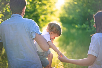 Family walking together on a sunny forest path in summer