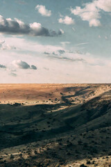 Naklejka premium Panoramic view of a misty desert canyon under a cloudy sky at sunset