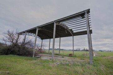 Abandoned farm in the Romagna countryside. Photo of the exterior and interior with ruined agricultural tools.
