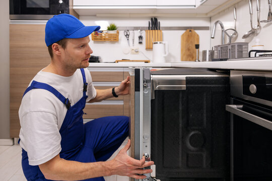 service worker installing integrated dishwasher in the kitchen. domestic appliance maintenance and repair