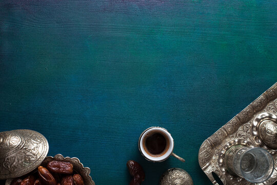 Cup of coffee, glass of water and bowl with date fruits on wooden table painted  blue-green. Top view. Ramadan background.