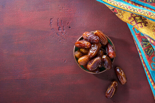 Bronze plate with dates on old red-brown wooden table. Ramadan background.  Flat lay.