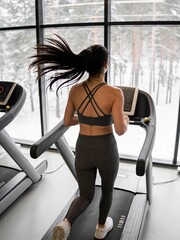 Fototapeta premium A woman running on a treadmill in a gym
