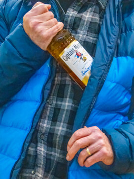 St Neots, UK - Friday 19th December 2025: A shoplifter putting a bottle of alcohol into his coat 