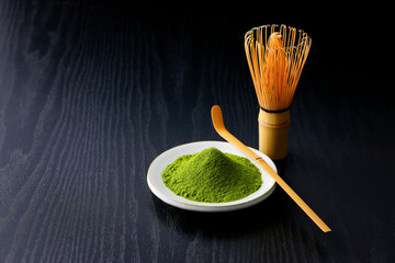 黒背景の木目に映える鮮やかな日本の抹茶の粉末　Vibrant Japanese matcha green tea powder on dark wood background