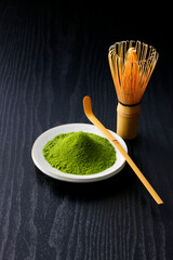 黒背景の木目に映える鮮やかな日本の抹茶の粉末　Vibrant Japanese matcha green tea powder on dark wood background