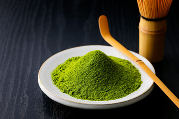 黒背景の木目に映える鮮やかな日本の抹茶の粉末　Vibrant Japanese matcha green tea powder on dark wood background