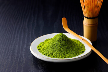 黒背景の木目に映える鮮やかな日本の抹茶の粉末　Vibrant Japanese matcha green tea powder on dark wood background