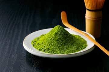 黒背景の木目に映える鮮やかな日本の抹茶の粉末　Vibrant Japanese matcha green tea powder on dark wood background