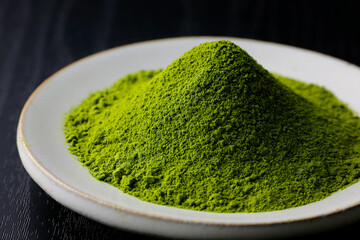 黒背景の木目に映える鮮やかな日本の抹茶パウダー　Vibrant Japanese matcha green tea powder on dark wood background