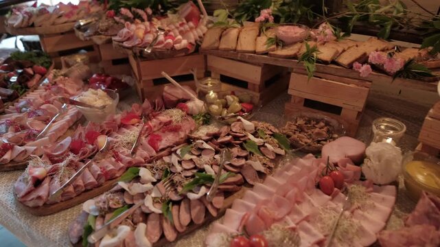 Rustic appetizer buffet featuring various cold cuts and meats arranged on wooden boards and crates. Wide static shot