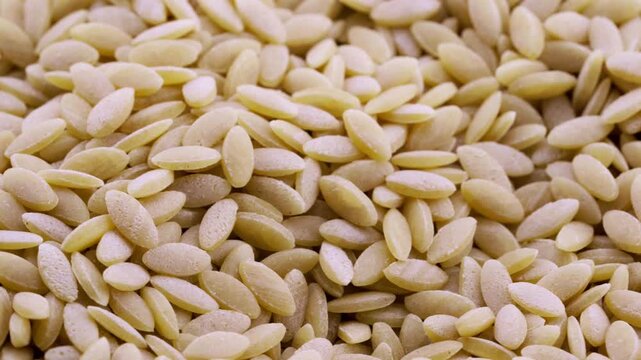 closeup macro raw risoni or rice shape pasta food background texture rotation turntable food video footage