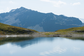 The calm waters with circular ripples created by the wind of the lake named "Lac Sans Fond", France, close to the border with Italy. High alpine mountain peaks on the background.