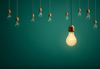 Glowing light bulb hanging on green background with copy space, innovative eco energy concept created by designer in studio for startup company promoting sustainable electricity solution