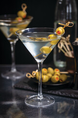 Dirty martini with olives on a pick on a dark background