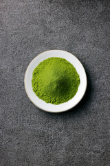 グレーのモダンな背景に映える鮮やかな日本の抹茶の粉末　Premium authentic Japanese matcha powder on a minimalist grey texture background