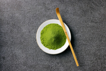 グレーのモダンな背景に映える鮮やかな日本の抹茶の粉末　Premium authentic Japanese matcha powder on a minimalist grey texture background