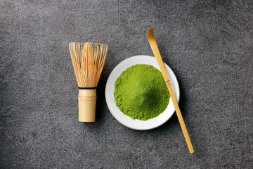 グレーのモダンな背景に映える鮮やかな日本の抹茶の粉末　Premium authentic Japanese matcha powder on a minimalist grey texture background