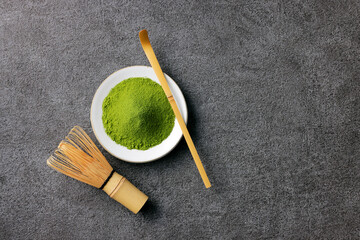 グレーのモダンな背景に映える鮮やかな日本の抹茶の粉末　Premium authentic Japanese matcha powder on a minimalist grey texture background