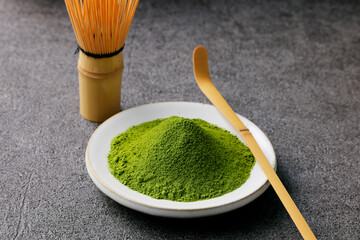 グレーのモダンな背景に映える鮮やかな日本の抹茶の粉末　Premium authentic Japanese matcha powder on a minimalist grey texture background