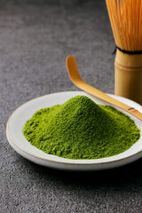 グレーのモダンな背景に映える鮮やかな日本の抹茶の粉末　Premium authentic Japanese matcha powder on a minimalist grey texture background