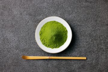 グレーのモダンな背景に映える鮮やかな日本の抹茶の粉末　Premium authentic Japanese matcha powder on a minimalist grey texture background